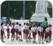 Imagem de professora com seus alunos uniformizados e em fila num ambiente externo