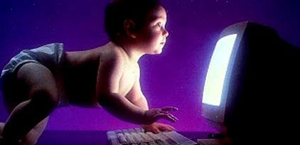 Foto de um bebê apoiado no teclado e olhando para a tela do computador