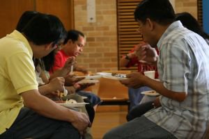 Vrios homens sentados segurando pratos de refeies