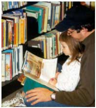 Pai-e-filha-em-biblioteca-com-livro-aberto