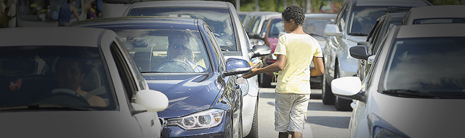 menino andando entre os carros parados no semforo