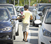 menino andando entre os carros parados no semforo