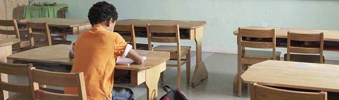 garoto sentado sozinho na sala de aula