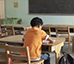 garoto sentado sozinho na sala de aula