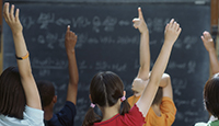 alunos com mos levantadas na sala de aula