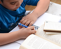 aluno estudando com caderno e livro sobre a mesa