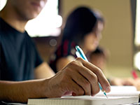 mo com caneta sobre o caderno em sala de aula